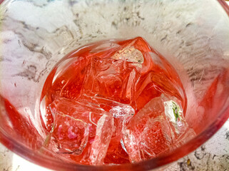 Red drink and ice cubes in glass