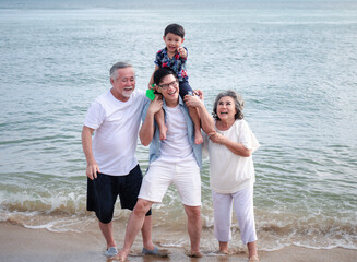 Happy multi-generation Asian family having fun in the sea on a beach holiday...