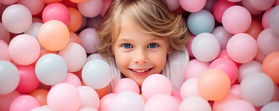 Young Boy Smiling in a Ball Pit With Pastel Colored Balls