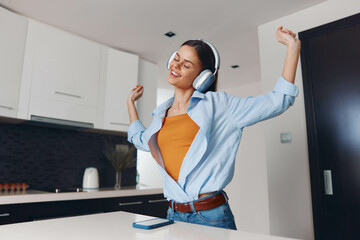 Woman Enjoying Music in Kitchen with Arms Outstretched While Standing on Counter listening to Music