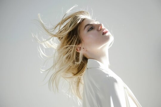 Beautiful woman with flowing hair in front of a white background, feeling the wind and movement concept
