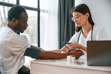 Female doctor measures blood pressure of a man