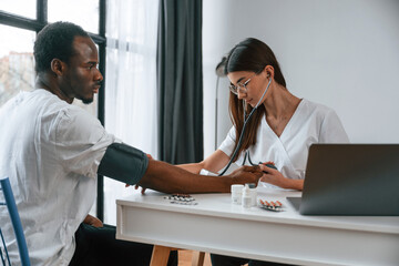 Healthcare conception. Female doctor measures blood pressure of a man