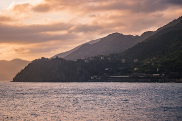 Fototapeta premium Mountains with mediterranean Corniglia village in lowlight and gradient in horizon at sunset, Cinque Terre ITALY