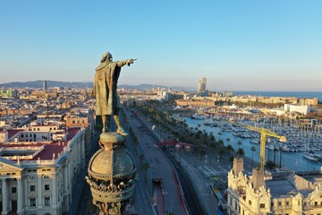 Christopher Columbus monument pointing towards America during the golden sunset in Barcelona, with the city background behind. Catalonia. aerial view