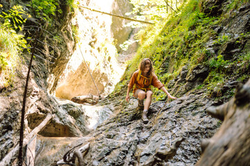 Adventure woman with a yellow backpack walks along a hiking trail against the backdrop of mountain...