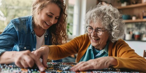 Joyful caregiver aiding elderly woman with puzzle in residence.