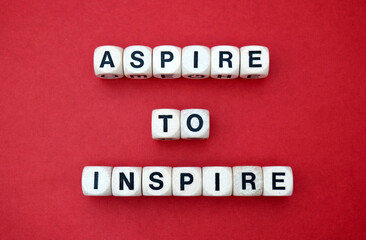 Inspirational mantra Aspire to Inspire  spelt using wooden word dice over a vibrant red cardboard...