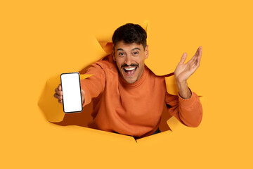 Man with moustache showing phone through torn paper