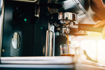 In a coffee shop espresso machine brews coffee. Fresh espresso pouring into glasses displaying modern coffee making technology. Flowing liquid steam smooth service in cafe.