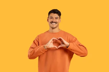 Tuinposter Man with moustache making heart shape with hands © Prostock-studio