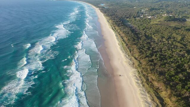 Majesty turquoise seascape. Foamy ocean waves roll and approach sandy beach. Top view from a drone.
