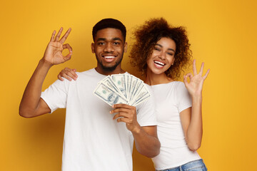 Happy african man and woman gesturing OK sign with lots of money