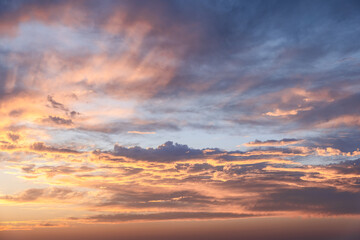The sky at sunset showcases a mesmerizing array of orange and blue hues, with clouds illuminated in...