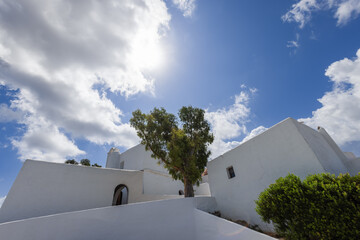 The white facade of Puig de Missa church stands out against a backdrop of azure skies and fluffy...