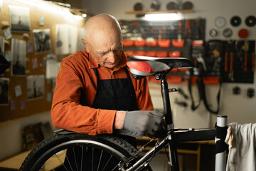 Elderly repair man in bicycle cycling workshop. Confident old bike mechanic, small business owner...