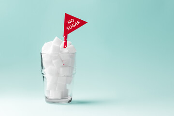 Glass full of sugar cubes with no sugar red sign on green background