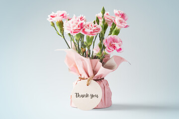 Pink carnation flower bouquet with thank you tag on vintage background