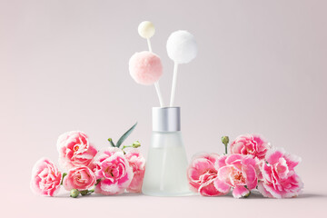 Fragrance diffuser and pink carnation flowers decor on pink background