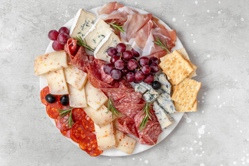 Charcuterie plate with Italian salami and prosciutto ham, with gorgonzrola cheese and pecorino cheese with herbs, served with olives and grapes.  Two glasses of  wine, appetizer platter for aperitif