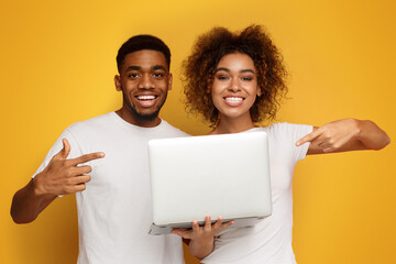 Happy african american couple showing their new laptop - 781283211
