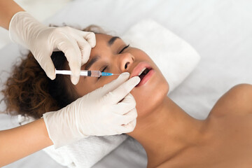 African-american woman getting injection in lips in clinic