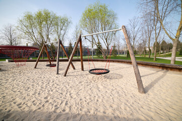 Swings on a sand-covered playground. Entertainment complex for children's games.
