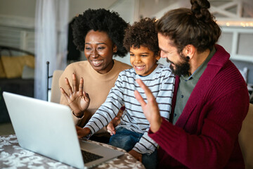 Happy multiethnic diverse family gathering around notebook and having fun during a video call - 781288677