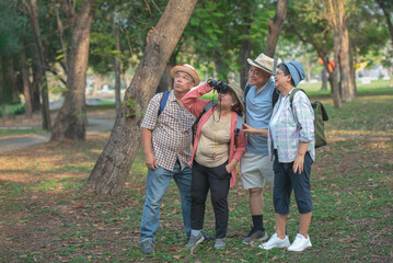 A group of Asian tourists backpacks, goes hiking, uses a camera to watch birds, and walks to see nature. Ideas for traveling to relax after retirement