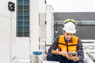 Male technical foreman in safety uniform inspects maintenance work holding a tablet to look at...