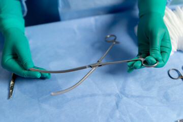 close-up in the operating room the hands of a doctor in green gloves hold surgical instruments