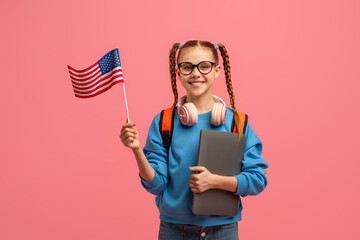 Smiling girl holding USA flag on pink background