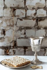Matzah and a silver goblet on a white table,