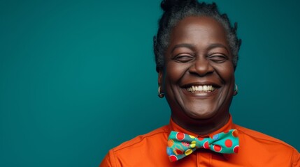 Joyful African Woman Smiling with Colorful Bow Tie on Teal Background.