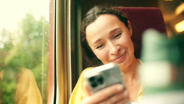 Happy woman makes a videocall on her smartphone in the train