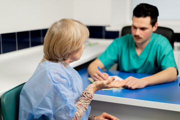 in a plastic surgery clinic a doctor consults an elderly woman making notes on paper
