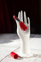 open red lipstick on a porcelain stand in the shape of a hand