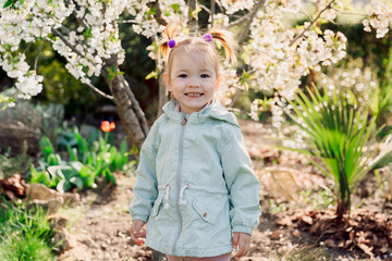 Smiling beauty girl in jacket in spring blooming garden.