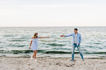 Man reaches out to a woman on sand sea. A couple in love is holding hands on seashore. Female and...