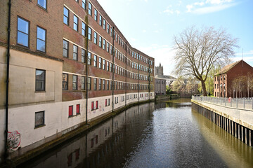 View of curved modern but rundown building and Wensum river at Duke's Palace Bridge in Norwich town...