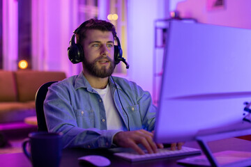 Focused gamer using PC in neon-lit room
