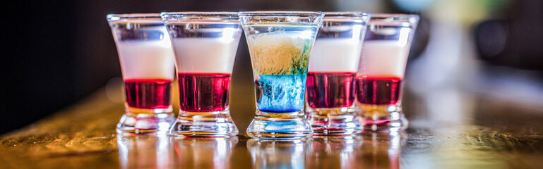 Collection of colorful shots on bar, set of alcohol mini cocktail shooters. Colorful shots at the club. Alcoholic drink in different colors. Set of alcoholic cocktails in shot glasses