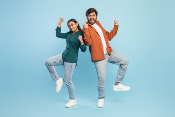 Energetic couple celebrating success on blue background