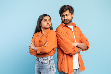 Couple with arms crossed in disagreement on blue background