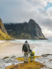 Family father and child hiking in Norway together exploring Lofoten islands adventure healthy lifestyle outdoor active vacations man with daughter enjoying Kvalvika beach landscape