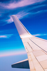 View of the part of a wing of an aeroplane or airliner in flight out of the window with blue sky...