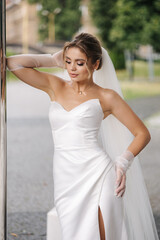 Portrait of beautiful and young bride in wedding dress standing outdoors