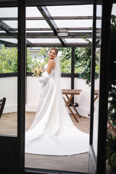 Beautiful bride in gorgeous wedding dress standing on the terrace and waiting for groom