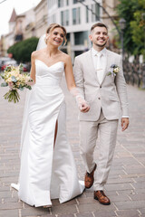 Newlyweds walking in the city centre in Europe. Beautiful wedding couple surrounded of old...