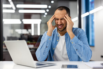 Stressed businessman with headache working late in office